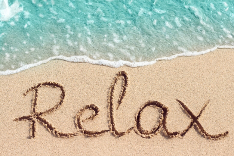 Word Relax is hand written on sand